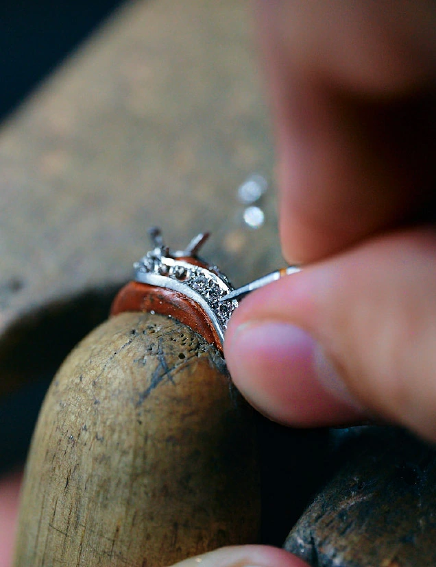 Gros plan d’un outil de sertissage ajustant les pierres d’une bague aux Ateliers GEM.