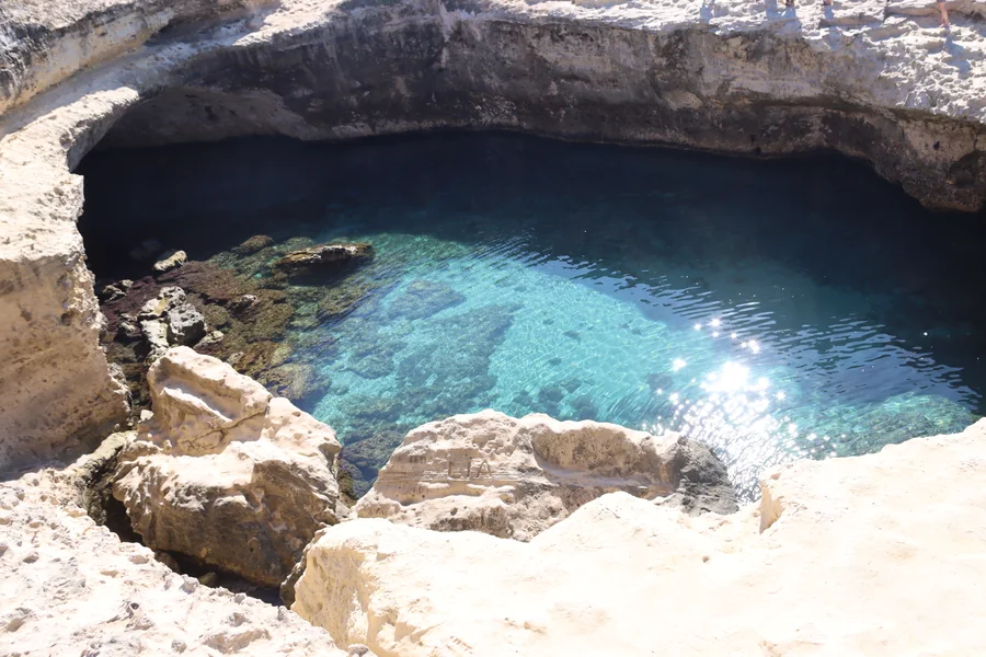 Bassin naturel de la Grotta della Poesia, entouré de roche calcaire à Roca Vecchia.