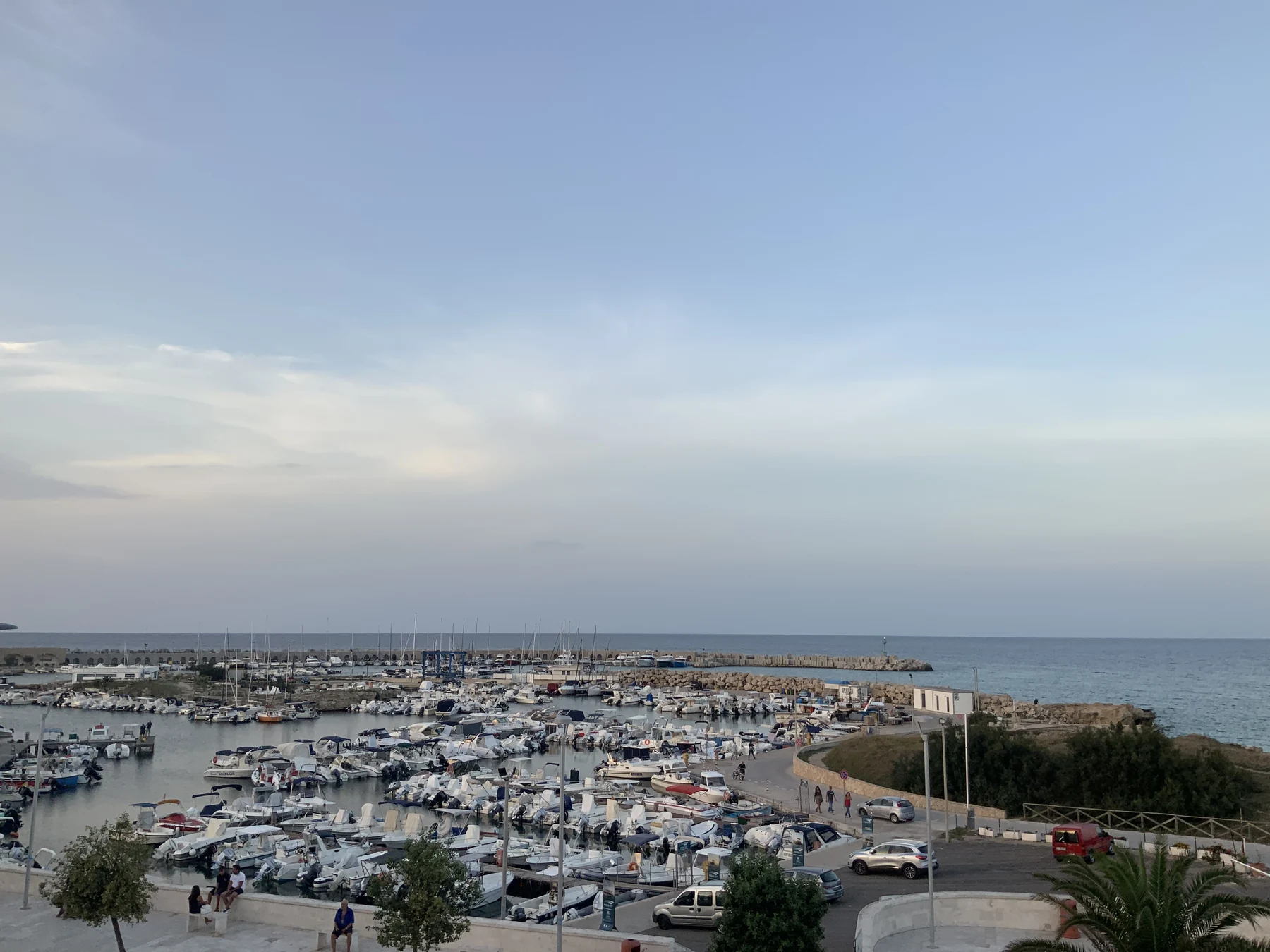 Port de San Foca avec ses bateaux, ses quais et la mer Adriatique en soirée.