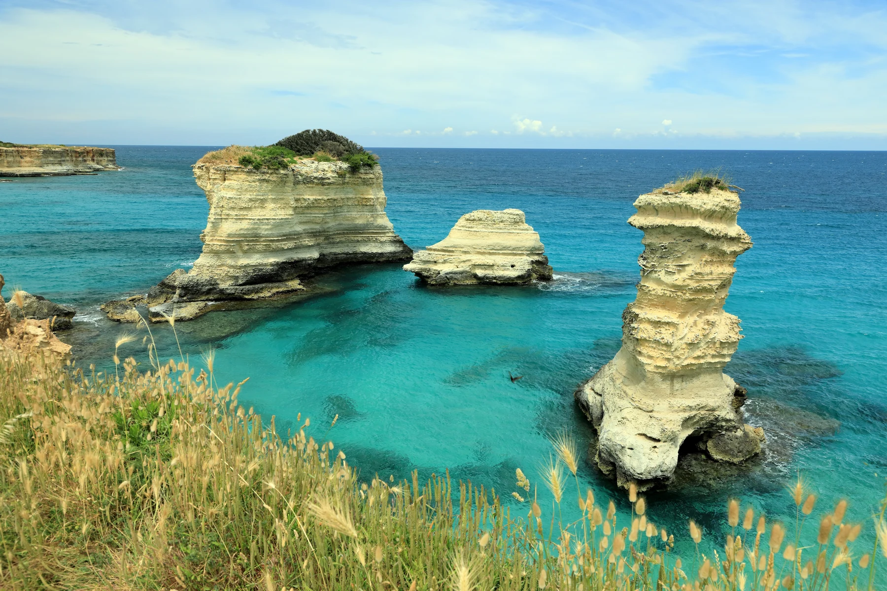 Faraglioni de Torre Sant’Andrea au-dessus d’une mer turquoise, avec Isola Piramide à gauche.